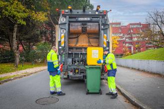 Deux éboueurs ouvrant une poubelle derrière un camion poubelle